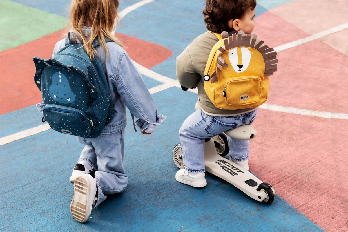 twee kindjes op de speelplaats met elk een schoolrugzak op hun rug