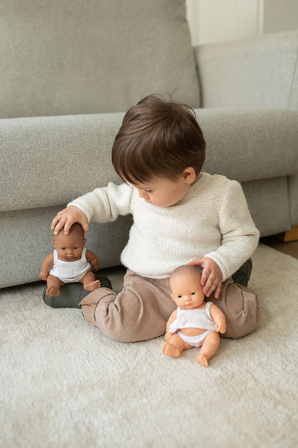 kindje zit op zijn knieën met 2 kleine popjes