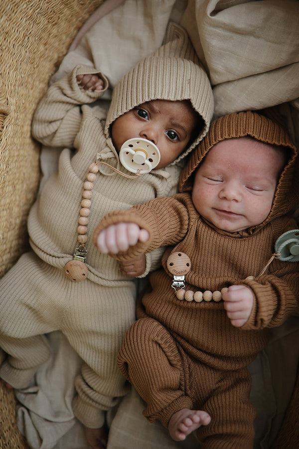 twee newborn baby's naast elkaar in een wieg met een fopspeen van frigg aan een tutketting van siliconen parels