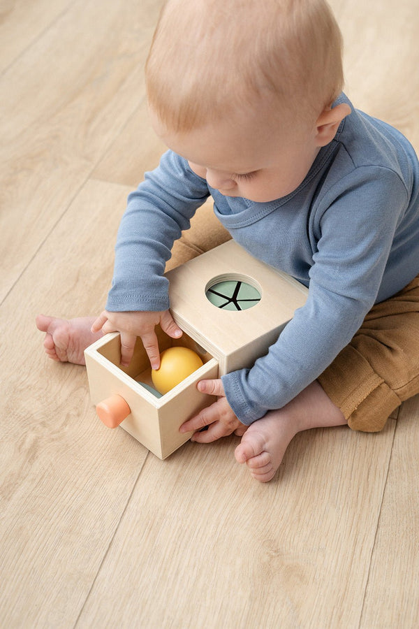 Baby zit op de grond met houten speelgoed en ontdekkersdoosje voor kleine ontdekkers van Done by Deer - In den Olifant