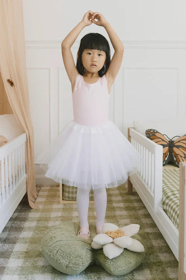 Meisje met zwart haar in balletpakje staat op een kussen van Swan Lake kussen en tapijt met ruitjes in de kinderkamer.