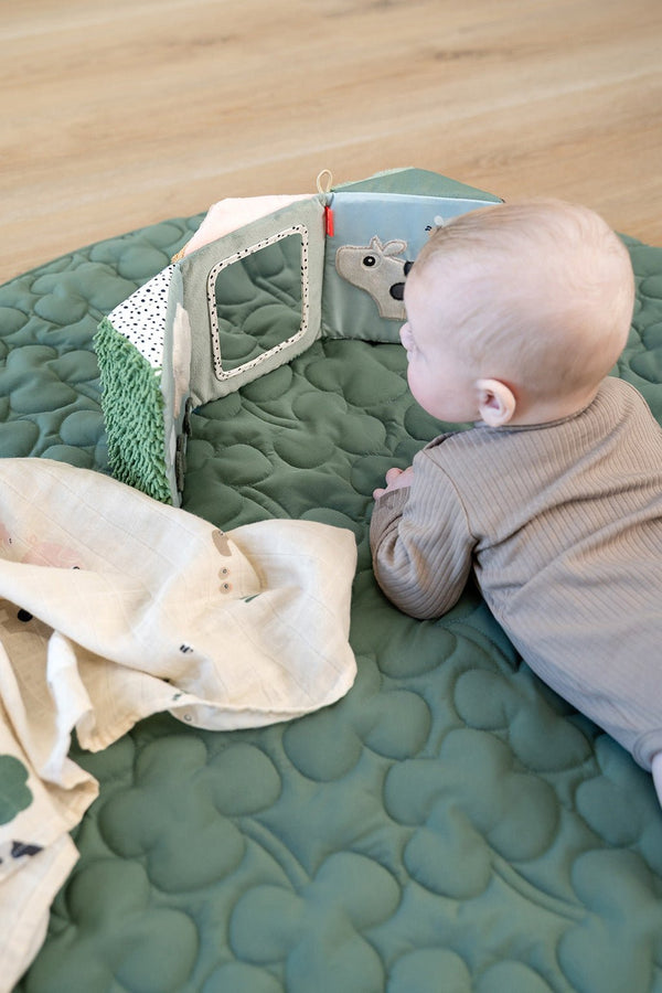 Groene speelmat met baby die op zijn buikje ligt voor tummy time met Done by Deer speelgoed en babyspiegel