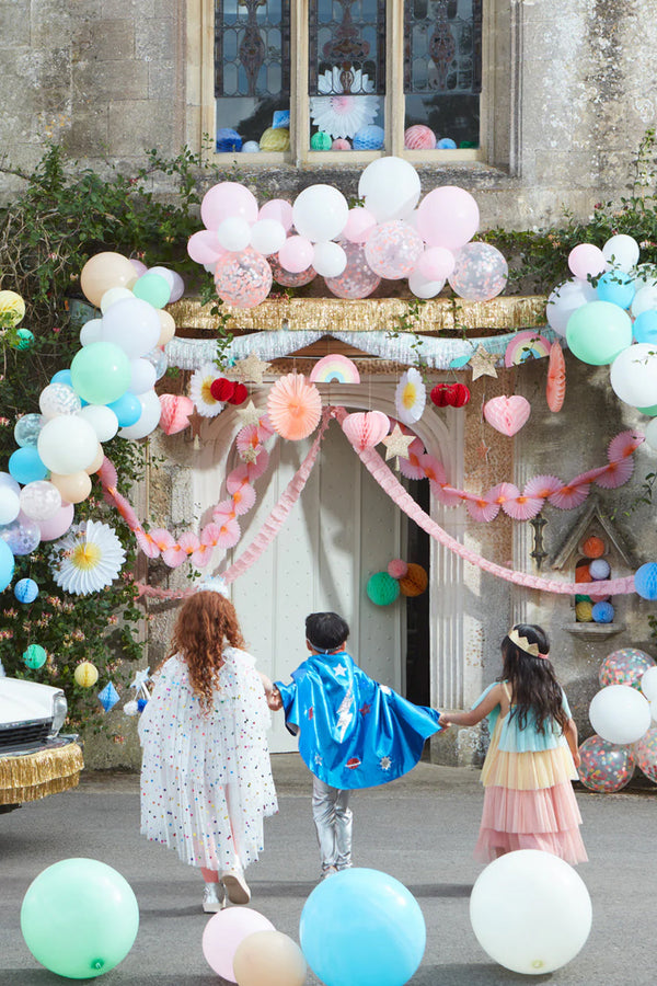 drie kindjes zijn verkleed en wandelen naar een voordeur versiert met ballonnen en slingers