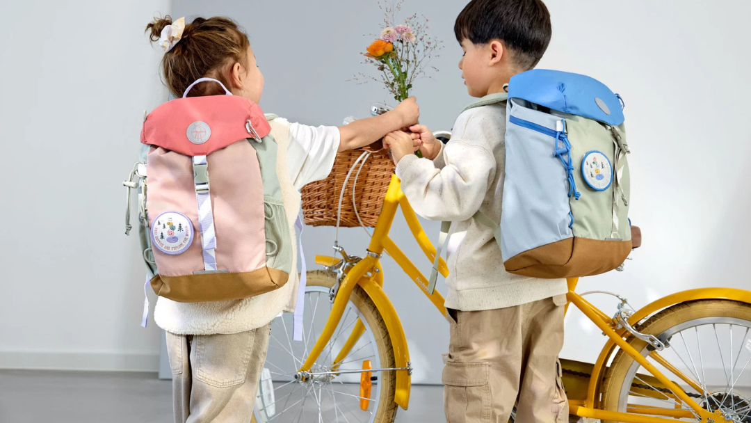 Kindjes op de rug met rugzakken en gele fiets